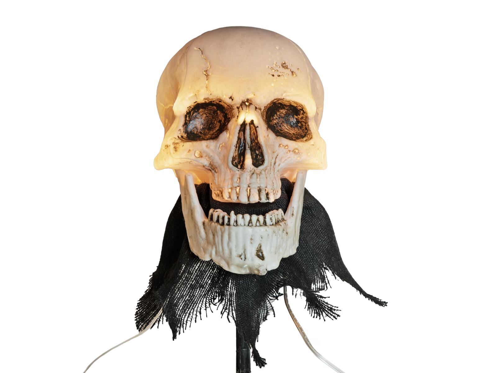 Kolme valaistua Halloween-pääkalloa maapiikeillä