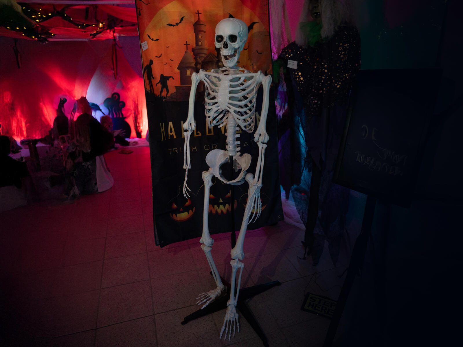 Luonnonvalkoinen seisova Halloween-luuranko mustalla jalustalla